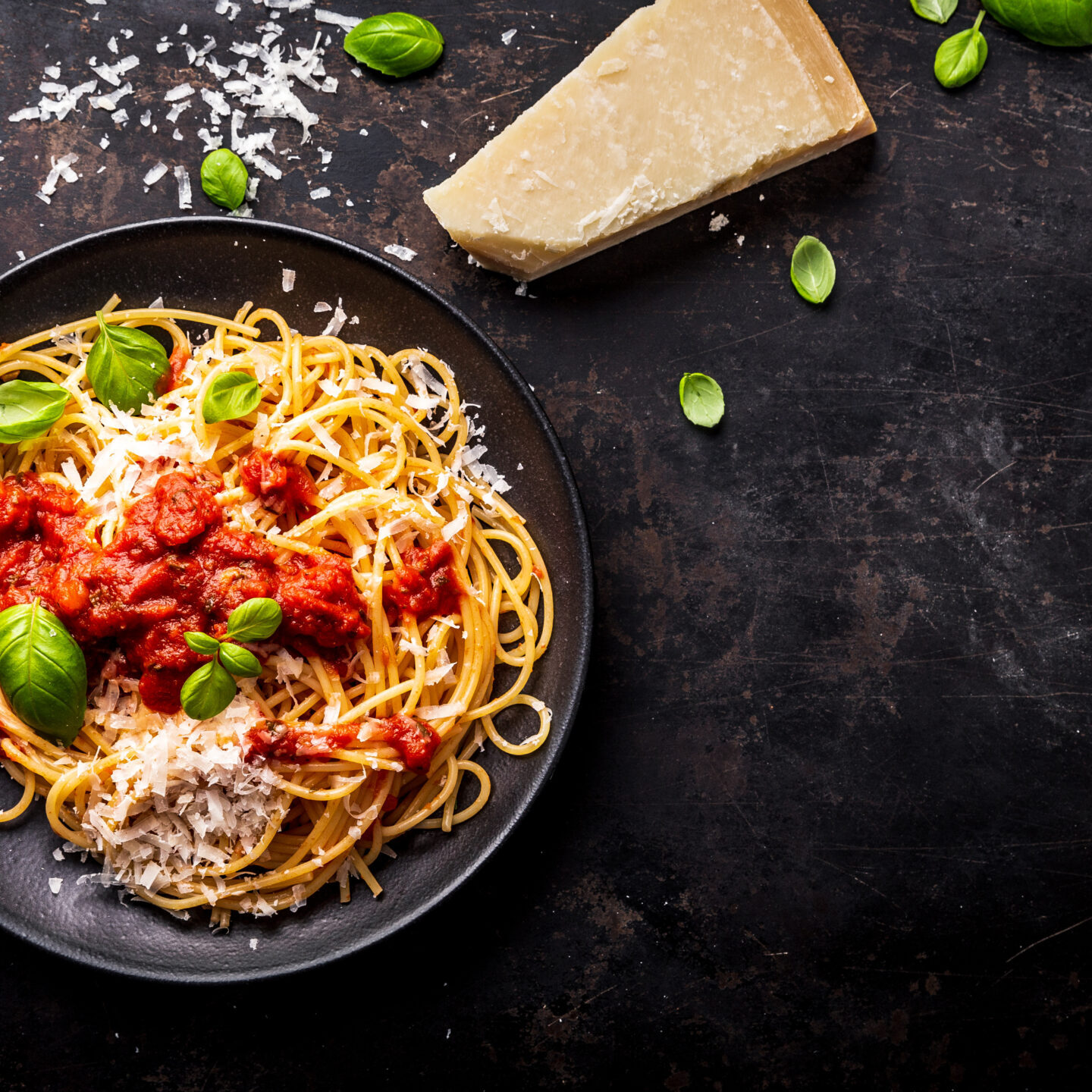 delicious appetizing classic spaghetti pasta with tomato sauce, parmesan cheese and fresh basil, top view